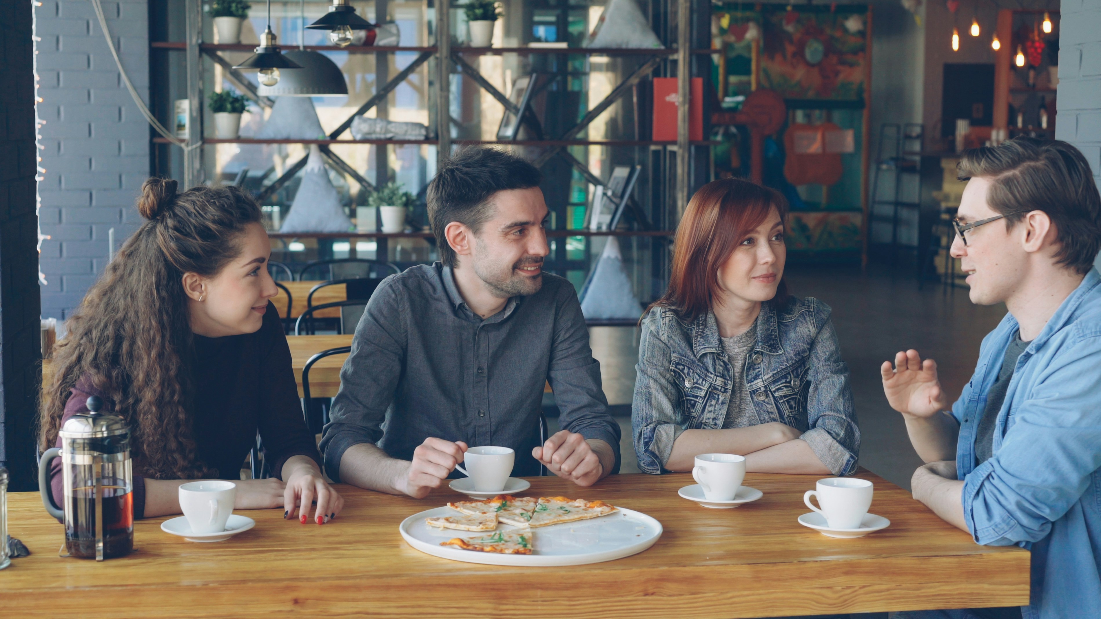 Friends sitting around a table chatting and having coffee together.
