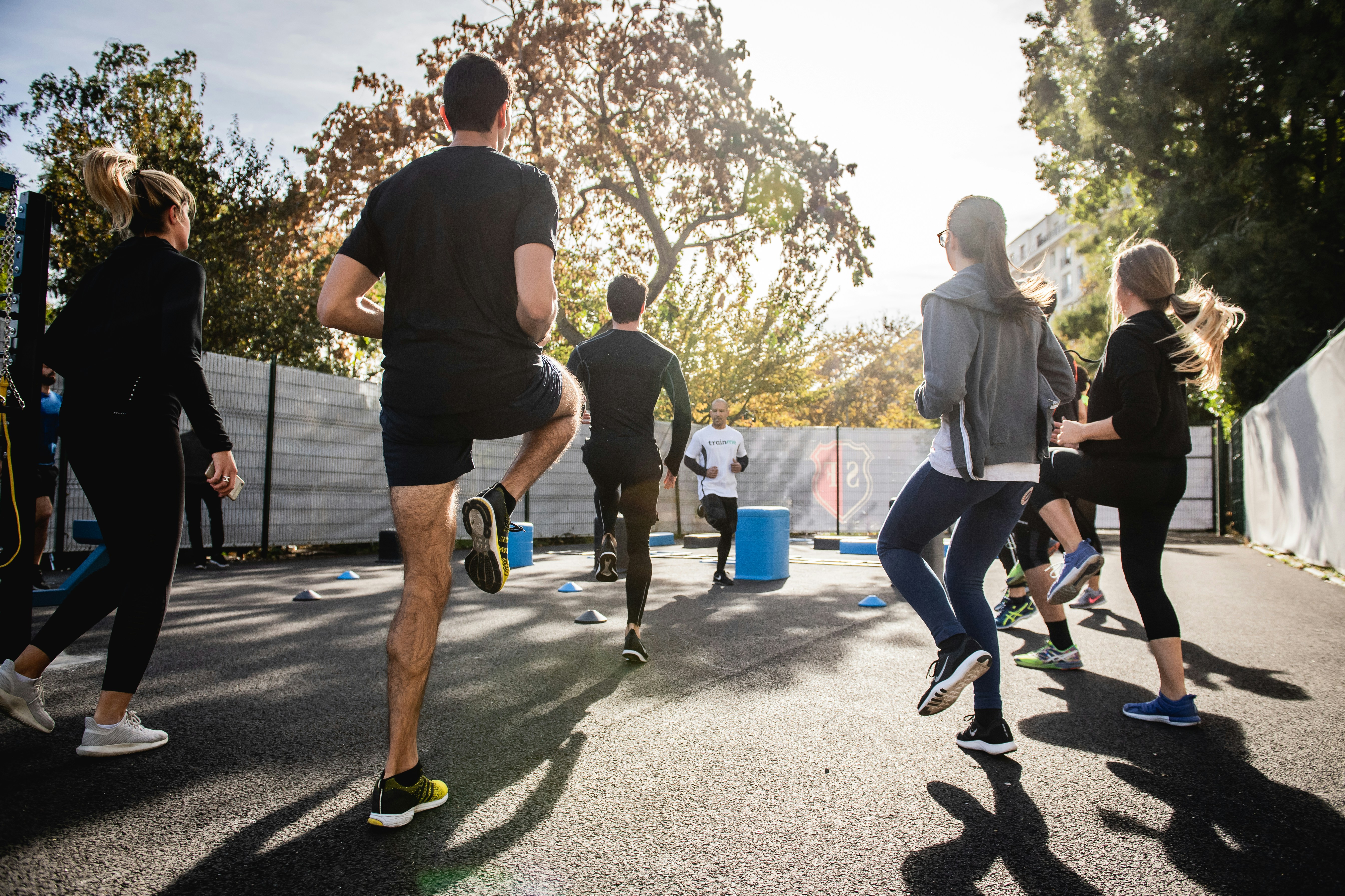 Group of people are jogging looking toward their coach.